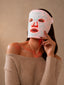 A woman wearing an Omnilux LED light therapy face mask.