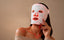A woman wearing an Omnilux LED light therapy face mask